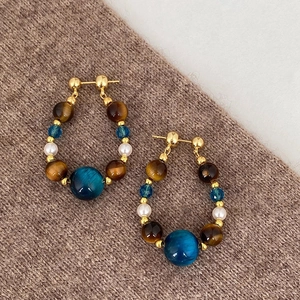 Détails de boucles d'oreilles vintage avec perles et œil de tigre sur un tricot marron