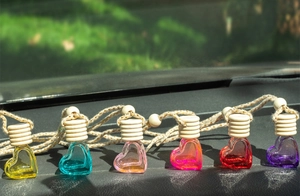 Close-up of heart-shaped glass perfume bottles with wooden caps on a car dashboard