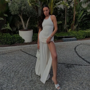 Détails de l'élégante robe longue blanche sans manches avec fente haute et tissu drapé
