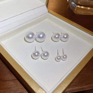 Set of four minimalist pearl stud earrings in various sizes displayed in a jewelry box