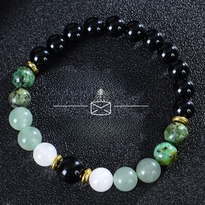 Detail view of tiger eye and malachite beads with Money & Success text on black background