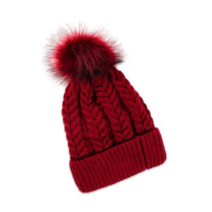 Close-up of dark red chunky cable knit beanie with a large matching faux fur pom-pom