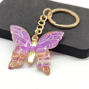 Macro shot of gradient purple resin butterfly keychain with elegant gold metal detailing