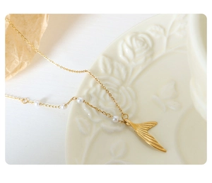 Macro shot of elegant gold mermaid tail pendant necklace with delicate white pearls