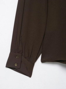 Detail of dark brown crepe shirt sleeves featuring elegant double gold metal buttons