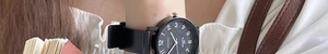 Close-up of minimalist black quartz watch with Arabic numerals on a wrist in a daily setting