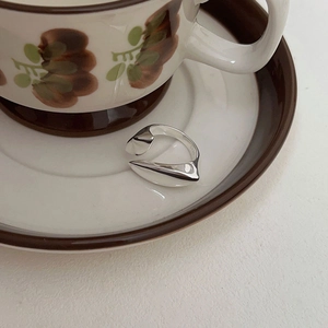 Macro detail of geometric S925 sterling silver open ring on a vintage ceramic tray