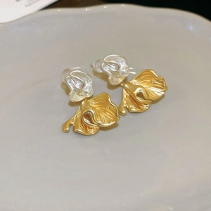 Macro detail of gold floral pearl earrings featuring irregular liquid metal texture