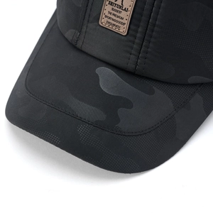 Dettaglio cappellino camouflage nero con trama ripstop e patch logo in pelle