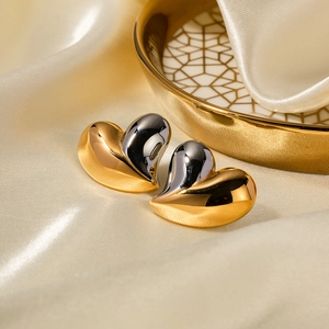 Polished 18K gold and silver heart-shaped stud earrings on a luxury silk background
