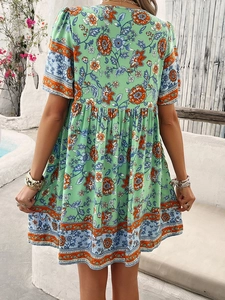 Back view of a green floral short sleeve dress in a Mediterranean style outdoor setting