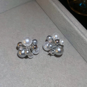 Macro detail of clustered white and grey pearls with sparkling zircons on velvet