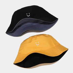 Detail of reversible bucket hats in black and yellow with white embroidered smiley faces