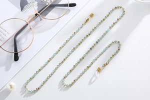 Detail of light blue beaded eyewear chain with gold accents and silicone loops
