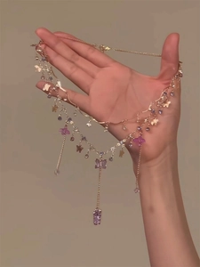 Detail of layered gold necklace with purple butterfly pendants and beaded accents