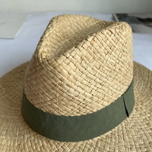 Detail of woven raffia straw hat with an olive green ribbon and texture close-up