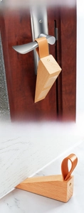 Detail of wooden door stopper with brown leather strap and anti-slip pad on marble floor