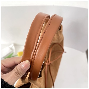 Detail of brown PU leather handle with precise stitching on a suede tote bag