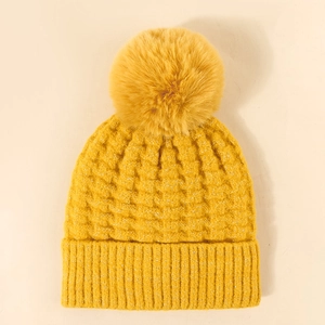 Winter knitted beanie in bright yellow with a fluffy pom-pom and warm ribbed knit pattern