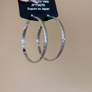 Macro shot of silver 925 hoop earrings with textured finish on branded jewelry card