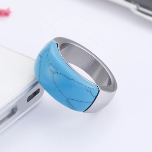 Macro detail of silver titanium steel ring with turquoise marble inlay on white surface