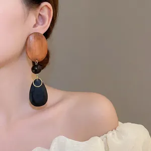 Vintage wooden oval and black waterdrop dangle earrings on female model in side view