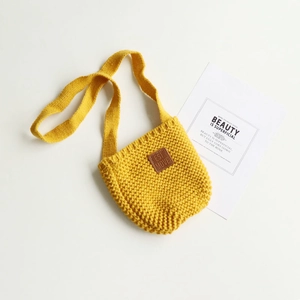 Dettaglio borsa a tracolla gialla in maglia per bambini con toppa in pelle e filato spesso