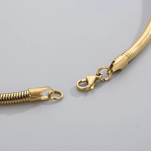 Close-up detail of the gold snake chain lobster clasp and metallic finish on the necklace
