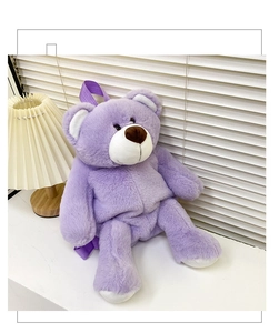 Detailed view of purple teddy bear plush backpack with soft texture in a cozy setting