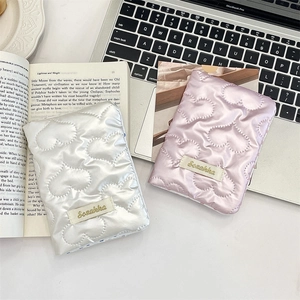 Detail of heart-quilted satin passport holders in pearl white and soft lilac colors