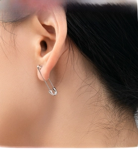 Close-up of S925 sterling silver safety pin earrings on model with visible hallmark