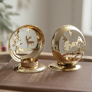 Golden Christmas iron candle holders with reindeer and tree silhouettes on books