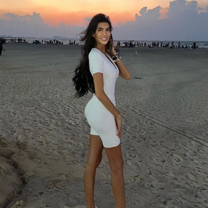 Slim fit white short sleeve V-neck romper showcased on a beach at sunset