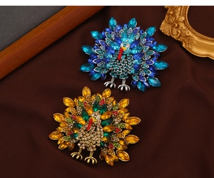 Detail of vintage peacock brooches with vibrant rhinestones in blue and amber tones
