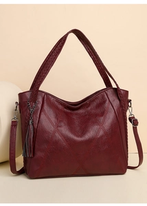 Detail of dark red quilted PU leather tote bag with elegant tassel and shoulder strap