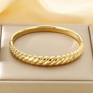 Detailed view of gold twisted croissant texture on stainless steel bangle with high gloss