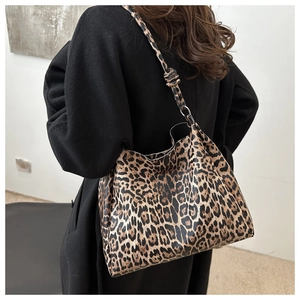 Leopard print tote bag with knotted shoulder strap shown on model with black coat