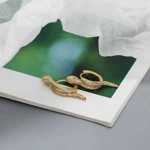 Detailed view of gold snake earrings with pave diamonds on card packaging