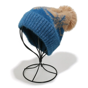 Detail of teal and camel knit hat with snowflake pattern and faux fur pompom