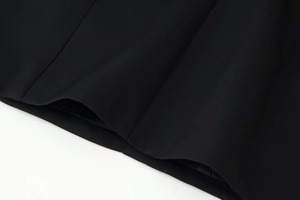 Close-up of the smooth black dress fabric hem with high-quality stitching detail