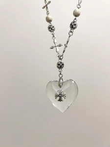 Close-up of vintage gothic cross pendant with crystal heart and marble beads necklace