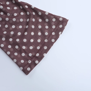 Gros plan du tissu en maille marron à pois montrant la texture et les coutures