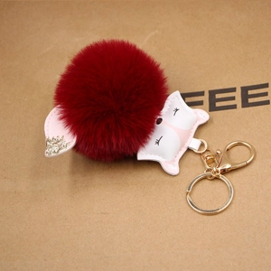 Detail of red plush ball keychain with pink PU leather fox head and gold glitter ears