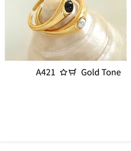 Close-up of vintage gold-tone U-shaped earrings with black stone and pearl on a shell
