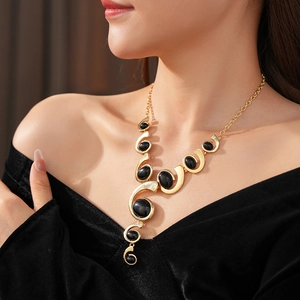 Elegance on model featuring a Y-shaped gold necklace with a black oval stone and swirl detail
