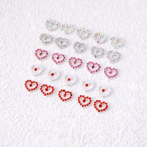 Alloy heart nail art charms with rhinestones and pearls on a white textured background