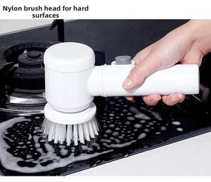 Electric cleaning brush with nylon bristles scrubbing foam off a kitchen stovetop surface