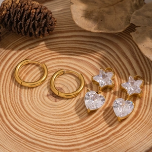 Détail de breloques étoile et cœur en acier doré 18K sur fond de bois rustique