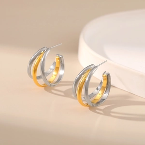 Detailed macro view of triple-layered C-shape earrings with gold and silver color contrast