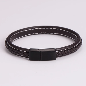 Detalle de pulsera de cuero negro trenzado con cierre magnético mate y costuras blancas